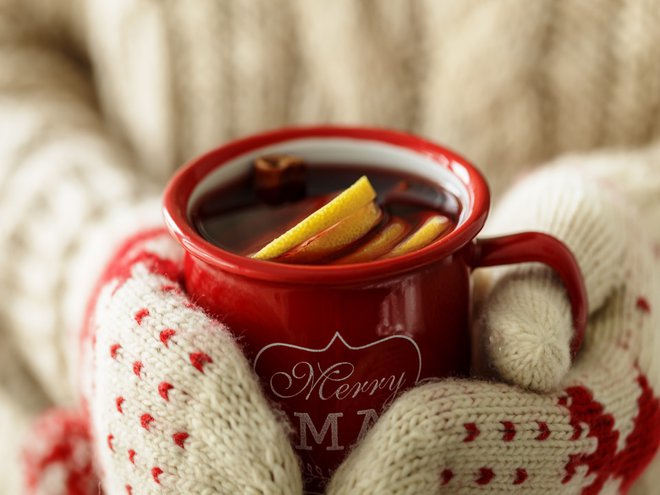 Closeup of anonymous person holding red mug saying Merry Xmas with hot spice wine.
